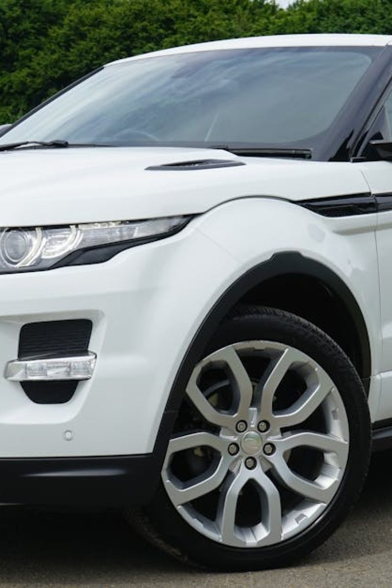 Stylish white Range Rover parked on a road in a green outdoor setting, showcasing its luxury design.